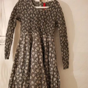  - Blommig långärmad klänning med knappar där bak. 