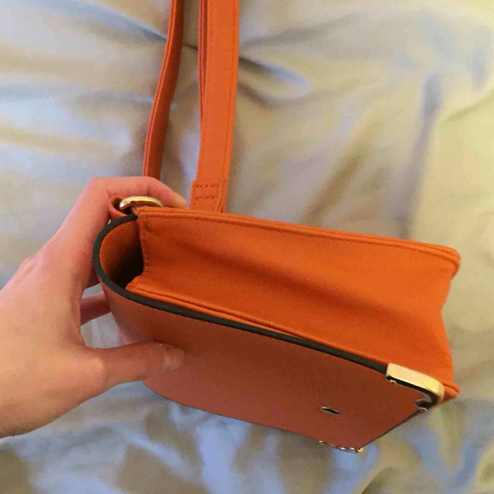 Snygg orange handväska, liten men lagom (rymmer tex cigaretter, telefon och en pocketbok!) retrokänsla och fin färg! Som ny, köpt här men inte kommit till användning 😥🧡🧡🧡. Väskor.