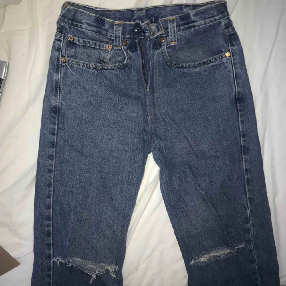 Levis 501 i gråaktig blå färg med två hål vid knäna. På jeansen står det storlek 38/32 men den är i verkligheten för 26/32. Antar därför att vintagebutiken jag köpte i har förminskat jeansen.. Jeans & Byxor.