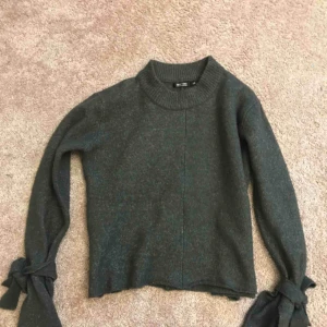  - Snygg stickad tröja i grå med knytningar på armen! Trendigt