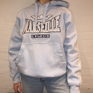 Vintage Hoodie Marseille Legend  - Dags för första släppet!                                             Vi säljer denna baby blue hoodie ifrån Marseille Legend. Priset är 299kr. Den är i storlek L och passar som en M. Personen på bilden är 165 och brukar ha på sig M. Det finns en del fläckar som inte riktigt syns om inte man kollar noga. Vi skickar bild vid intresse av köp. Kontakta oss på Plick eller vår Instagram @wanderetro. Om flera visar intresse blir det budgivning. Köparen står för spårbar frakt på 66kr. 🤍