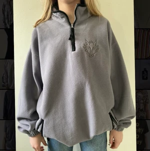 Grå fleece - Grå fleece med halvzip och broderat tryck fram och bak!