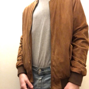 Mocka Bomber Jacka  - En brun bomber jacka i imitation mocka, varumärket ”lefties”. Storlek L.