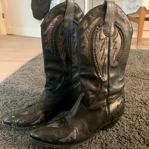 Svarta cowboyboots - Jättefina och trendiga cowboyboots! Passar dig med skostorlek 38/39. Finns tecken på användning och är lite uppskrapade på högra ovansidan. 
