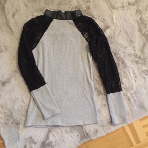 Spets tröja - Ljusgrå färg med svart spets på ärmar. Stl XL men det e felaktigt. Stl motsvarar XS/S. Nyskick!