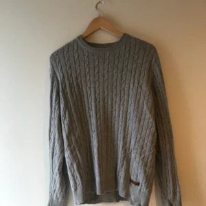 Bondelid kabelstickad - Grå kabelstickad tröja från Bondelid med brunt lädermärke nere vänster.  Bra skick, priset kan diskuteras