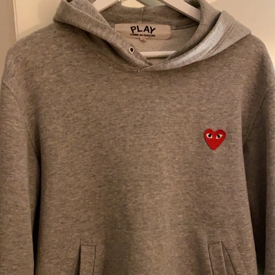 En grå PLAY hoodie med rött hjärta från Comme des Garçons. Köpt på NK för 2400 för några veckor sedan. I princip nyskick använd fåtal gånger. Inga fläckar, hål eller liknande. St M. Ledande bud 750. Hoodies.