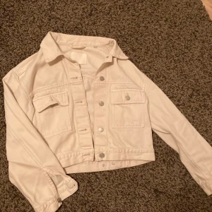Jeansjacka  - Beige jeansjacka, kort modell. Slutar precis innan höfterna. 