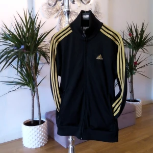 Adidas tröja - Snygg tröja, svart med guld och jättefin passform 😃 står storlek 164, passar dock S. Fickor med dragkedja och även 2st innerfickor Finns i Västerås 🌸🌸🌸