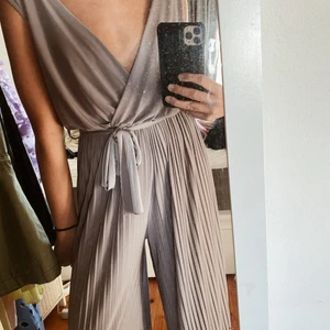 Beige/grå Byxdress - Säljer denna byxdressen i stl S/M. Den går i stuket grå/beige. Inköpspriset låg på 600kr i en spansk popup butik och jag säljer den för 350kr. Den är i superbra skick och använd 1 gång. Jag är 168cm lång 💜