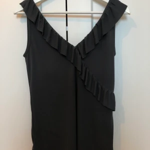 Mörkgrå topp  - En fin mörkgrå topp, med väldigt mjukt och härligt material. Toppen har en ganska djup urringning på fram och bak. Toppen är endast använd två gånger och är i mycket fint skick/som ny. Köparen står för frakten.