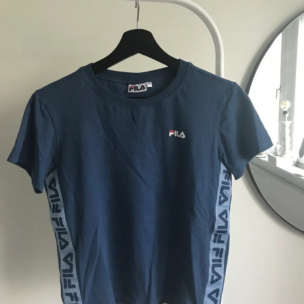 Blå Fila t-shirt som köptes för cirka 300kr säljes nu för 70kr. Fortfarande i bra skick knappt använd. Priset kan diskuteras och köparen står för frakten💕. T-shirts.