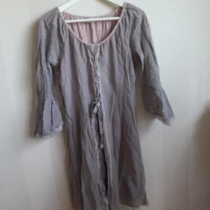  - Klänning i grå/gammelrosa i storlek 38 med spets och snörning framtill