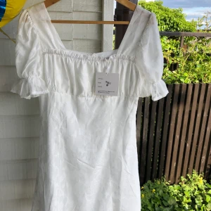 Vit klänning med fina detaljer! - Köpt från Verge Girl men var tyvärr för liten på mig. Aldrig använd, prislapp kvar. Originalpris: 96$, säljer för 400kr. Frakt tillkommer.
