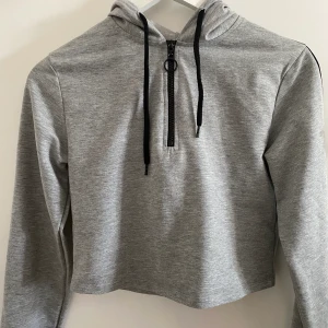 Grå NA-KD hoodie - En grå hoodie med half zip från nakd. Materialet är inte så tjockt så det är mer som en tröja. Köpte för mindre än ett år sen och bara använt fåtal gånger, men fortfarande fott som ny! 💕 Köpare betalar för frakt!!