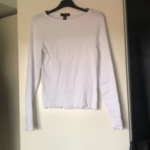 Vit tröja - Vit ribbad tröja med krulliga ärmar och nedre kant, smal åtsittande modell, aldrig använd eftersom den är för liten för mig, köpt på asos. Pris kan diskuteras, köpare betalar frakt ( måste bort annars skänks den)