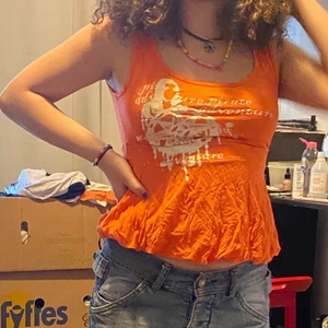 Orange linne - Ett orange linne med en liten kjol och text på. Köparen står för frakten