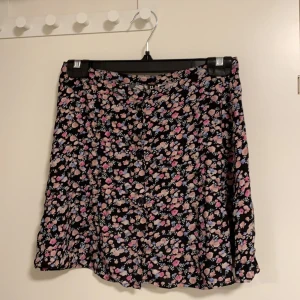 Kjol, storlek 38 - Söt blommig kjol. Man knäpper den med knappar, blommor i olika färger. Använd men i nyskick 