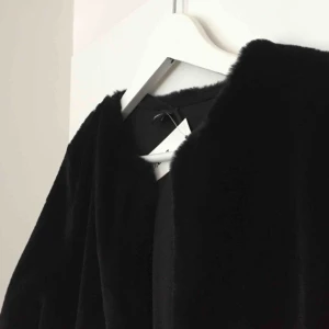  - Jacka/kofta i fuskpäls, helt oanvänd. Storlek S. Köparen står för frakt