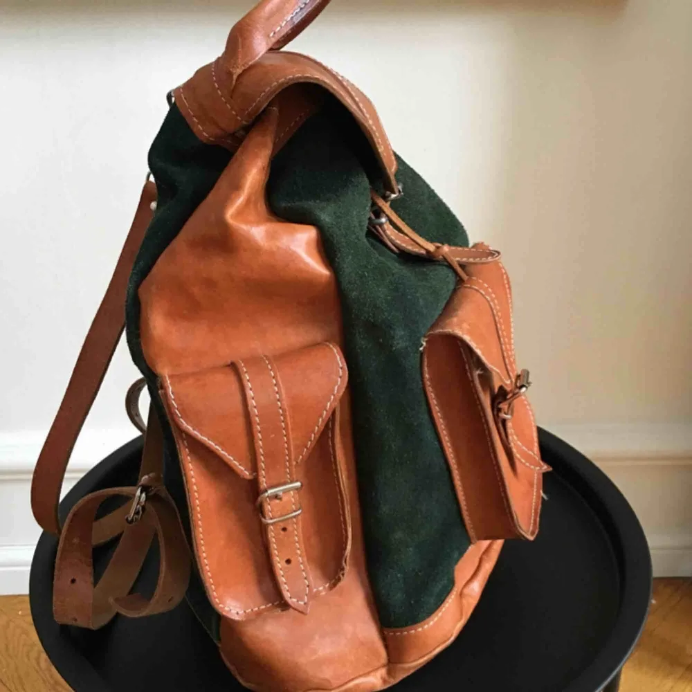 Säljer denna fina ryggsäck i väldigt fint och bevarat skick. Grön mocka med bruna läderpartier, rymlig rygga med djup på ca 40 och bredd ca 30.  2 sidofickor och en framtill.   Bjuder på frakt! . Väskor.