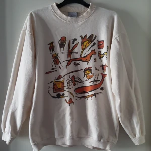  - Vintage vit sweatshirt med roligt tryck. Har en liten svag röd fläck framtill som syns på andra bilden, kanske går bort i tvätten. Finns i Örebro men kan skickas om köparen står för fraktkostnaden på 75kr.