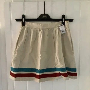  - En gräddvit kjol!  En vacker lite "retro" kjol med ränder på! Dragkedja på ena sidan. Den är ursprungligen från forever 21, men jag har köpt den på Emmaus, men har tyvärr aldrig fått användning för den, och den är i jättefint skick! 