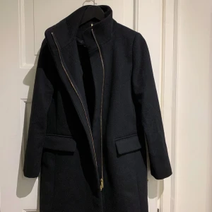 MQ kappa 34 Stockh lm - Svart ullkappa med fina gulddetaljer och hög krage. Riktiga fickor utanpå som aldrig öppnats, innerficka. Storlekslappen saknades när jag köpte och den var en stl för liten (jag har en i samma stl som jag inte kan ha just nu).