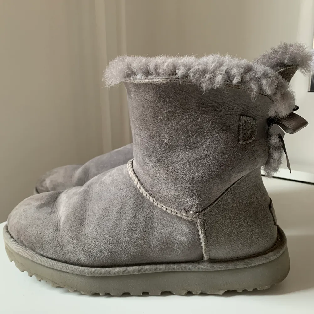 Gråa uggs med rosetter i bak. Sparsamt använda men har lite fläckar i fram (bild 3). Inköpta på uggs egna butik i usa för 2200 kr. Skor.