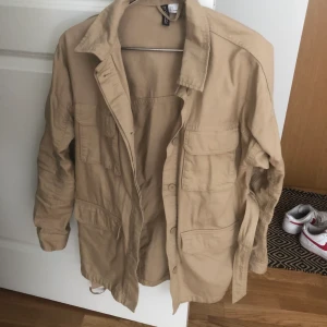 Beige jacka från hm. - Jacka med band som går att knyta i midjan. Använd ett fåtal gånger. Stolek: S