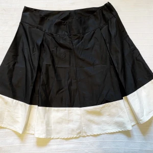 Fin veckad kjol i svart och krämvit - Svart och krämvit brett veckad kjol i mycket bra skick. Sitter fint i midjan och har vackert fall.