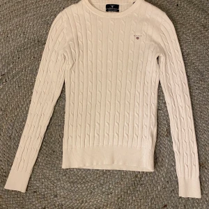 Gant Cable Crew, stickad, off white  - Koftan har en normal passform för de som har storleken XS och en hyfsat tightare passform för de som har S i storlek. Tröjan är knappt använd och i ett fint skick. Nypris är 1195. Skicka pm för fler bilder. Kan tänka mig att sänka priset 