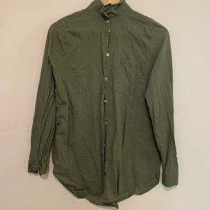 Militärgrön skjorta - Mörkgrön skjorta i strl 36 från H&M divided. Skrynklig på bilden men försvinner lätt vid strykning! Paketpris vid köp av tre skjortor: 200 kr för tre.