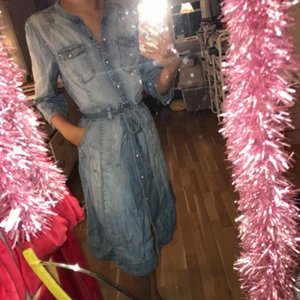 Jeans klänning med fickor - Jeansklänning med fickor från Lindex. Storlek 40 men passar mig som har XS/34 då midjebandet går att spänna åt. Säljes för 100 kr. Köparen står för eventuella fraktkostnader.