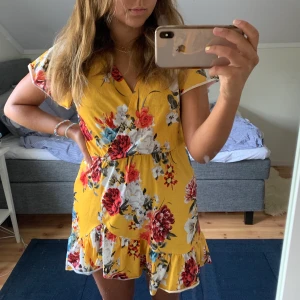 Gul klänning - Gul omlottklänning med blommor på! Utmärkt skick:)