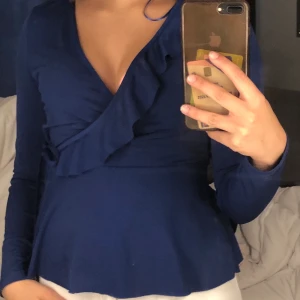 Lång ärmad tröja  - En omlott långärmad blå tröja med volang och snörrig