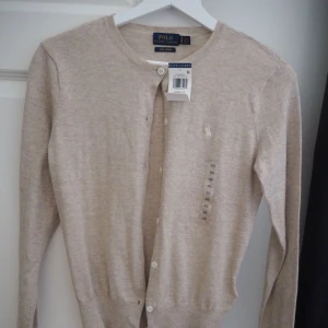  - VAD: Kofta cardigan från Ralph Lauren. Beige med knappar  STORLEK: XS SKICK: NY! Lapparna är dock borttagna då jag tvättat den!
