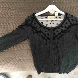  - Grå kofta med trekvartsarmar, och svarta spetsdetaljer runt kragen och en bit ner på armarna. Köpt från Anthropologie i USA. Originalpris ca 1200kr. 
