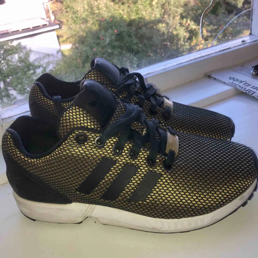 Guld och svarta skor från adidas, adidas torsion. Använda fåtal gånger, ser ut som nya.  Kan mötas upp eller skicka för 75kr.😊. Skor.