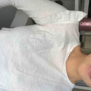  - En långärmad vit tröja med volanger på ärmarna, tröjan är köpt på barnavdelningen men sitter som XS, frakt tillkommer 😊