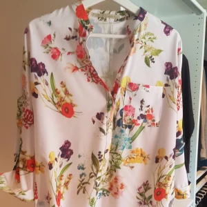  - Mönstrad blusinspirerad tröja. Längre baktill 