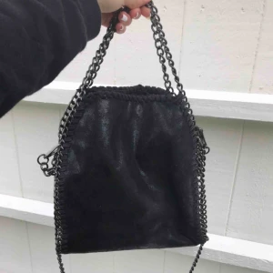  - Svart väska med kedja. Liknar Stella McCartney. Man kan ändra hur lång man vill kedjan ska vara på sidorna vilket jag gjort så det syns men man kan göra så storleken på kedjan passar så som man vill ha de.