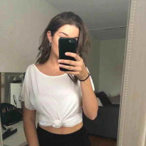  - En vit lite längre t-shirt som går att knyta upp om man vill. ”Öppningar” på axlarna. Köparen står för ev frakt:)