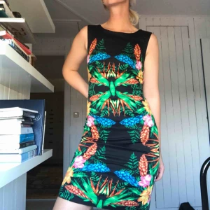  - Cocktailklänning från Warehouse. Svart satin med blommotiv på. Klassisk modell med båtringning i halsen. Går till strax över knät på mig, jag är 177cm lång. Smal och snäv passform med slits mitt bak. Köparen står för frakt eller möts i Gbg ✨