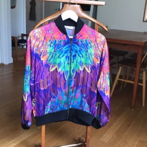  - Den ultimata festival jackan! Färgglad ziptröja med abstrakt, fjärerliknande mönster (framförallt på ryggen). Materialet är tunt, silkeslent. Endast använd en gång. 