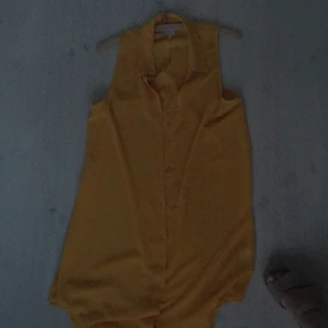  - Gul, ärmlös skjorta/tunika från monki i svalt material. Skitsnygg att ha öppen till ett par jeansshorts/kjol. Använt ett fåtal gånger och är i bra skick. Frakt ingår ej i priset. 