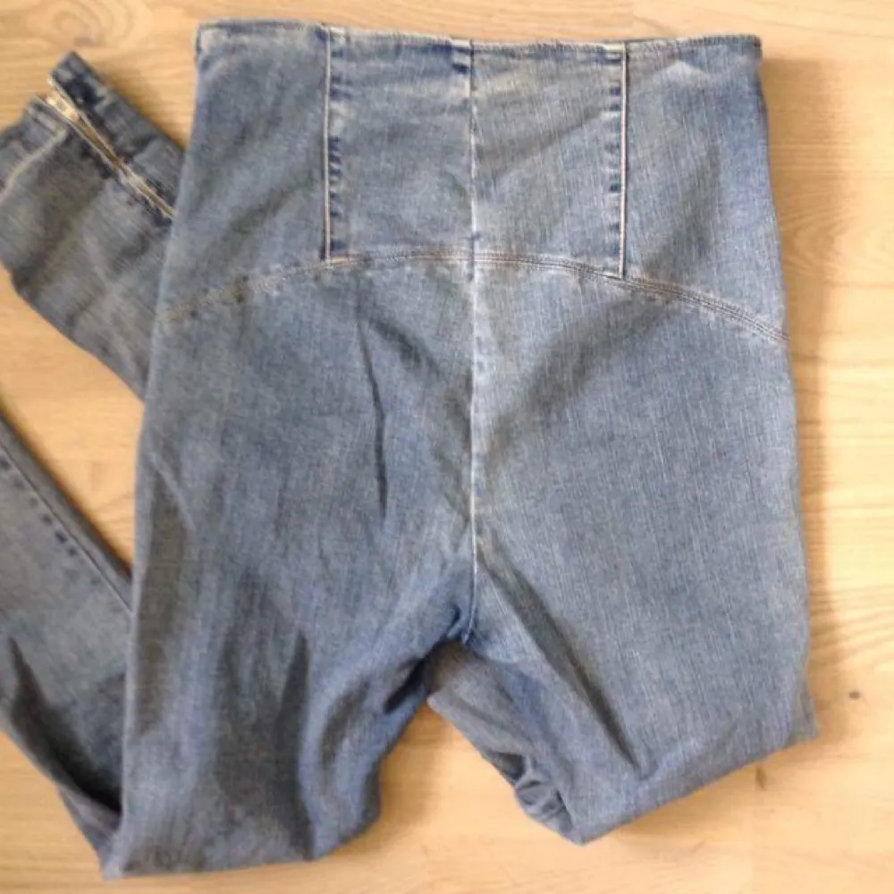 Högmidjade ljusblå jeans i tight stretchig modell från Whyred. Dragkedja vid byxslut samt på sidan istället för gylf och knapp.. Jeans & Byxor.