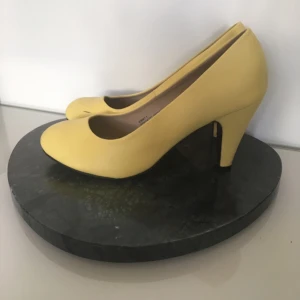  - Gula pumps i fejkskinn. Säljs pga för breda för mina smala fötter.   Endast använda 3 gånger, är i gott skick men har något märke.   Klacken är ca 7,5-8 cm.   Köpta för 2 år sen på Modcloth.  Kan möts upp i Stockholm eller centrala Uppsala. Vid frakt betalar köparen.