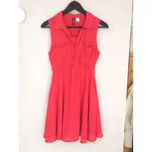 Hallon röd/rosa klänning från H&M Divided i storlek 34. I fint skick, med två bröstfickor.