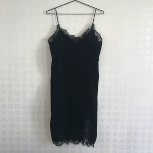 Sammetsklänning med spetsdetaljer - Få en boost för självförtroendet inför festen med denna snygga sammetsklänning från Gina Tricot. Snygga att styla med en vit t-shirt under. Knälång. Köparen står för frakten.