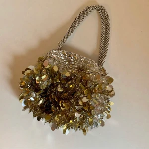 Vintage silver paljettväska - Liten paljettväska, Vintage. Mått: H 19 cm x B 21 cm x D (öppningen) 4 cm. Men är rymlig och större nertill.